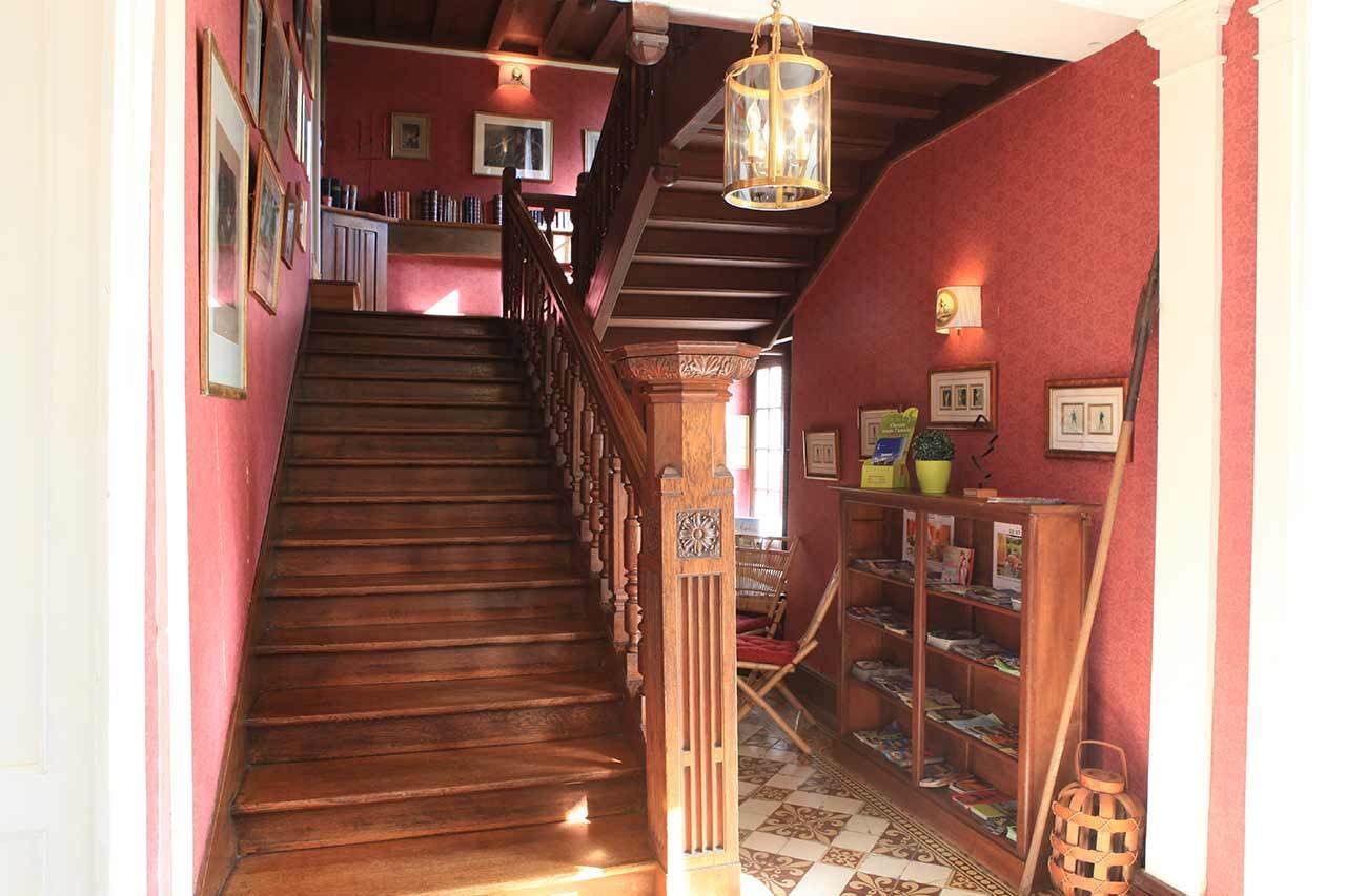 A staircase with wooden steps and a railing, leading to a landing with bookshelves and a hanging light fixture.