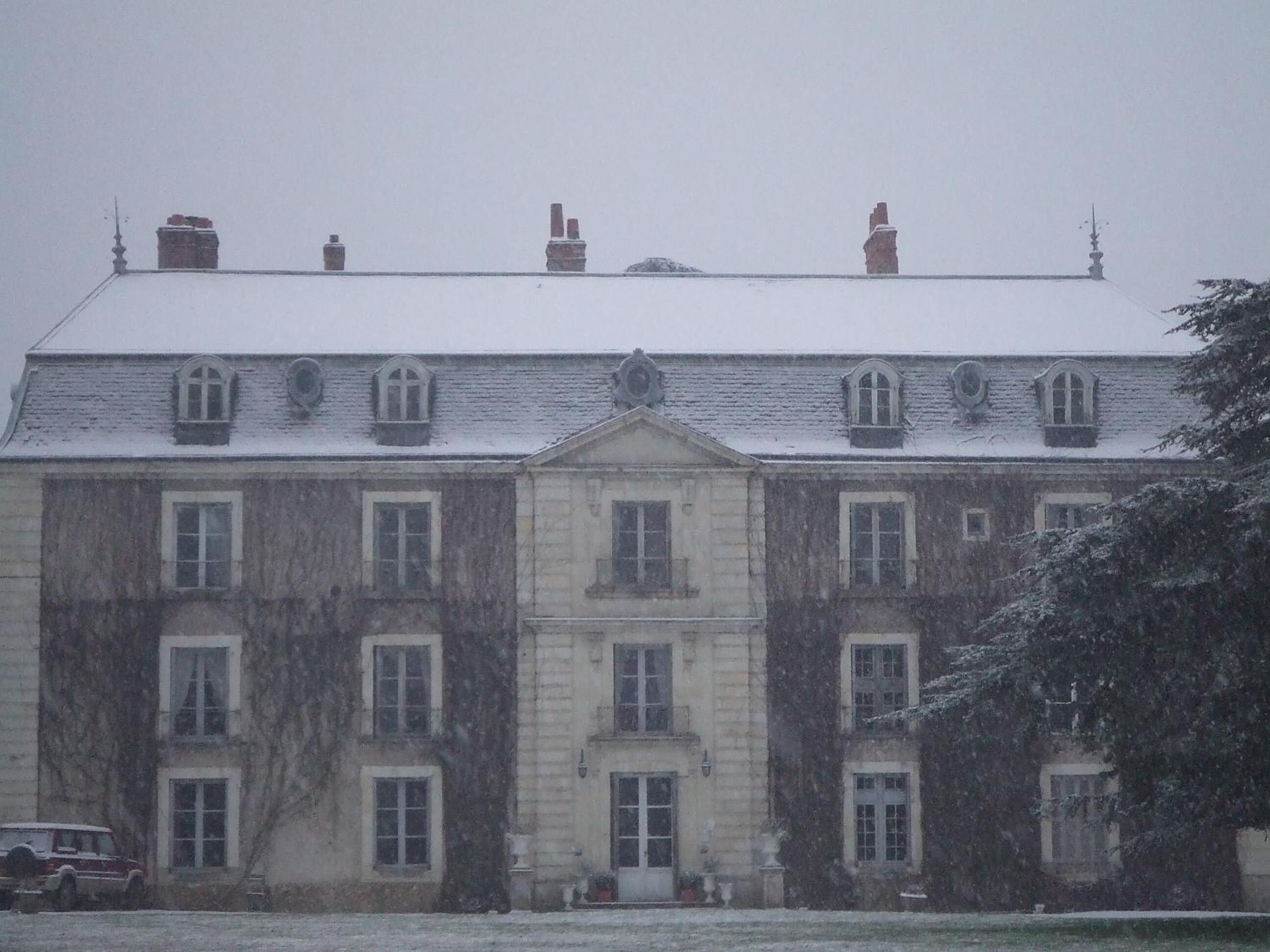 Ein großes, historisches Gebäude mit zahlreichen Fenstern und einer symmetrischen Fassade, das einen zentralen Eingang und ein mit Schnee bedecktes Dach zeigt.