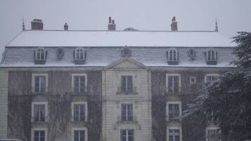 Ein großes, historisches Gebäude mit zahlreichen Fenstern und einer symmetrischen Fassade, das einen zentralen Eingang und ein mit Schnee bedecktes Dach zeigt.