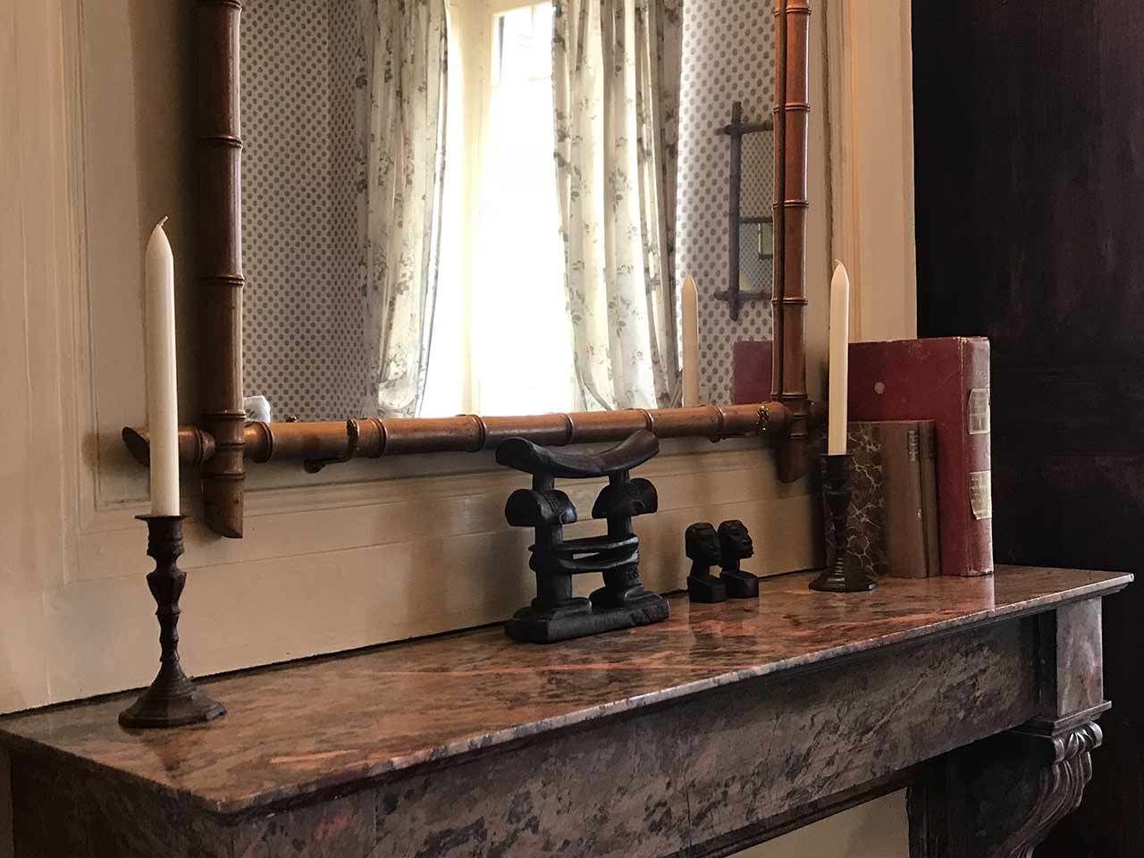 A marble table with a mirror, two candles, and a decorative object.