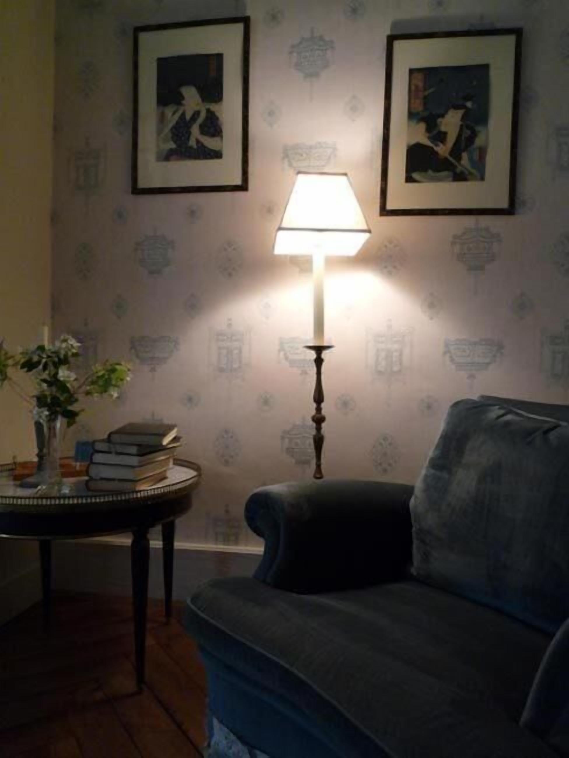 A room with a blue sofa, a table with books and a vase, and two framed pictures on the wall.