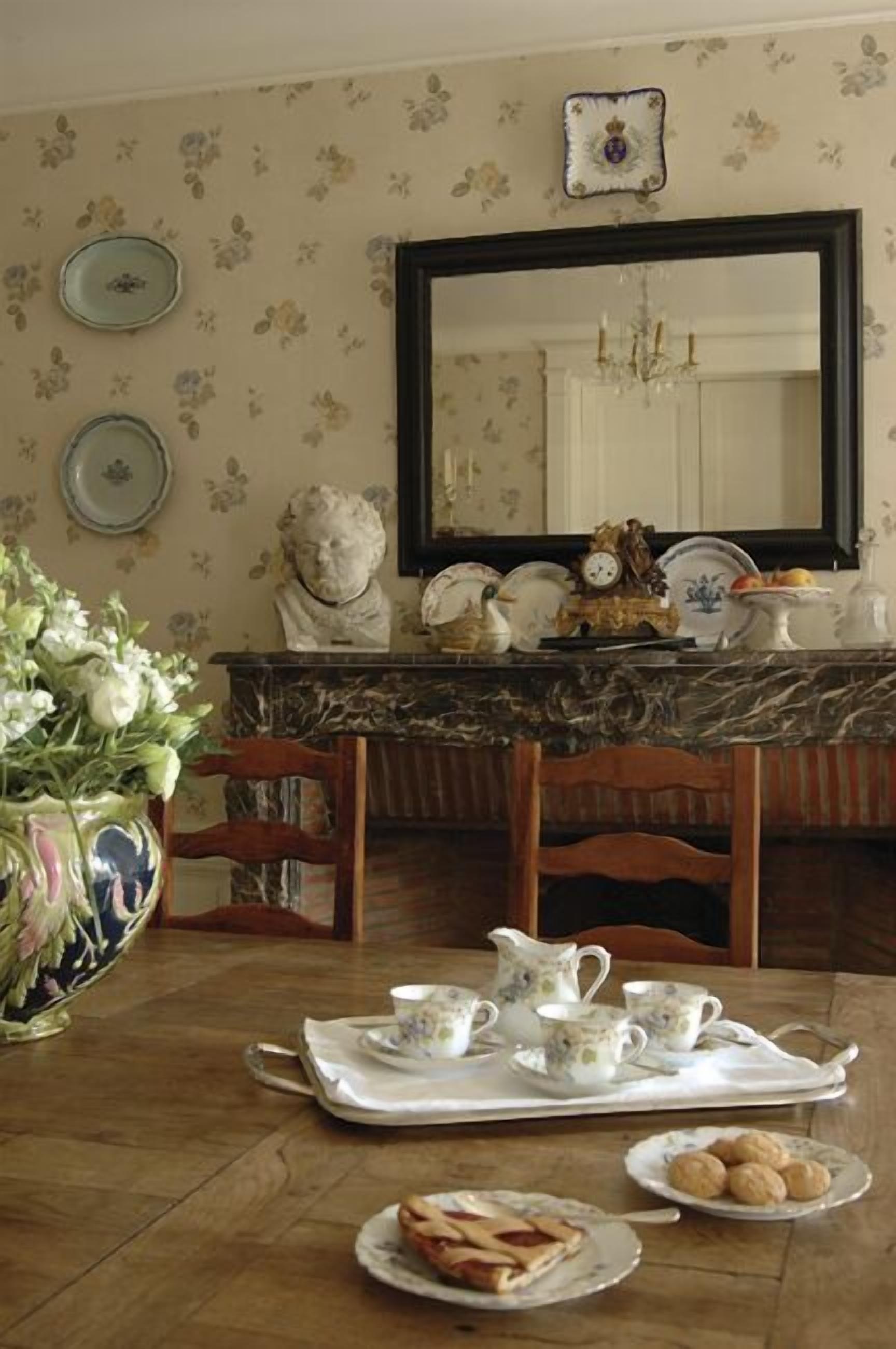 Un coin repas avec une table en marbre, un papier peint à motifs floraux et un grand miroir au-dessus du comptoir.