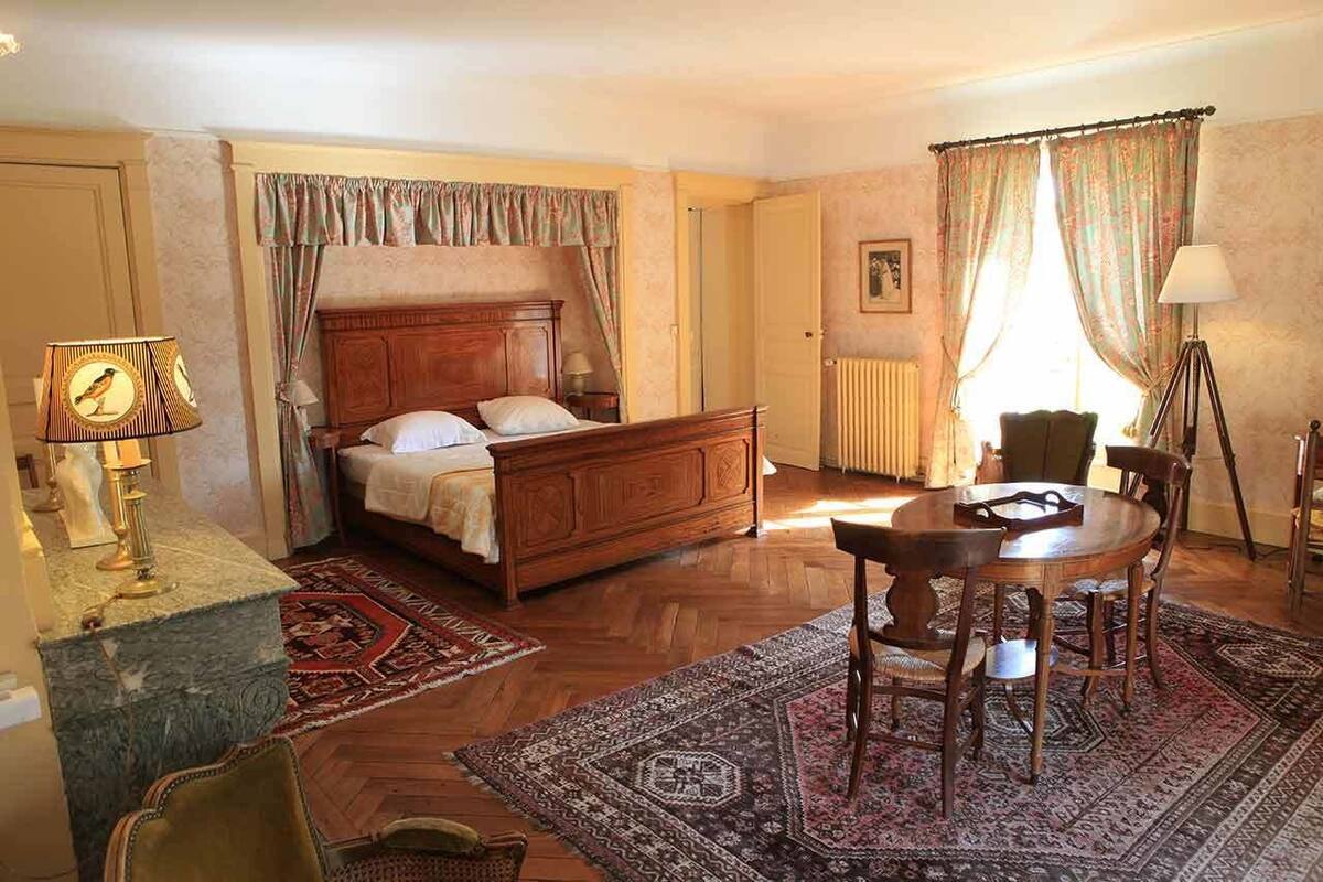 Une chambre à coucher avec un lit en bois, une table à manger avec des chaises, une lampe et un radiateur.