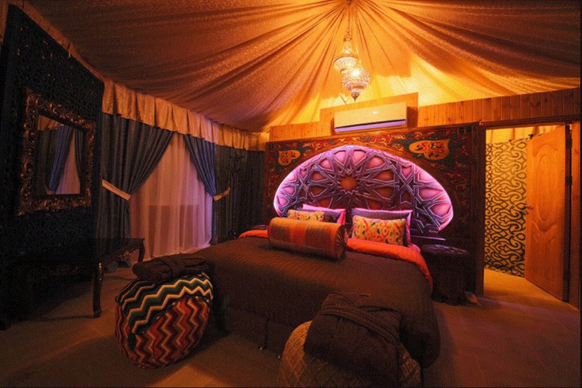 A room with a large bed, a chandelier, and patterned walls.