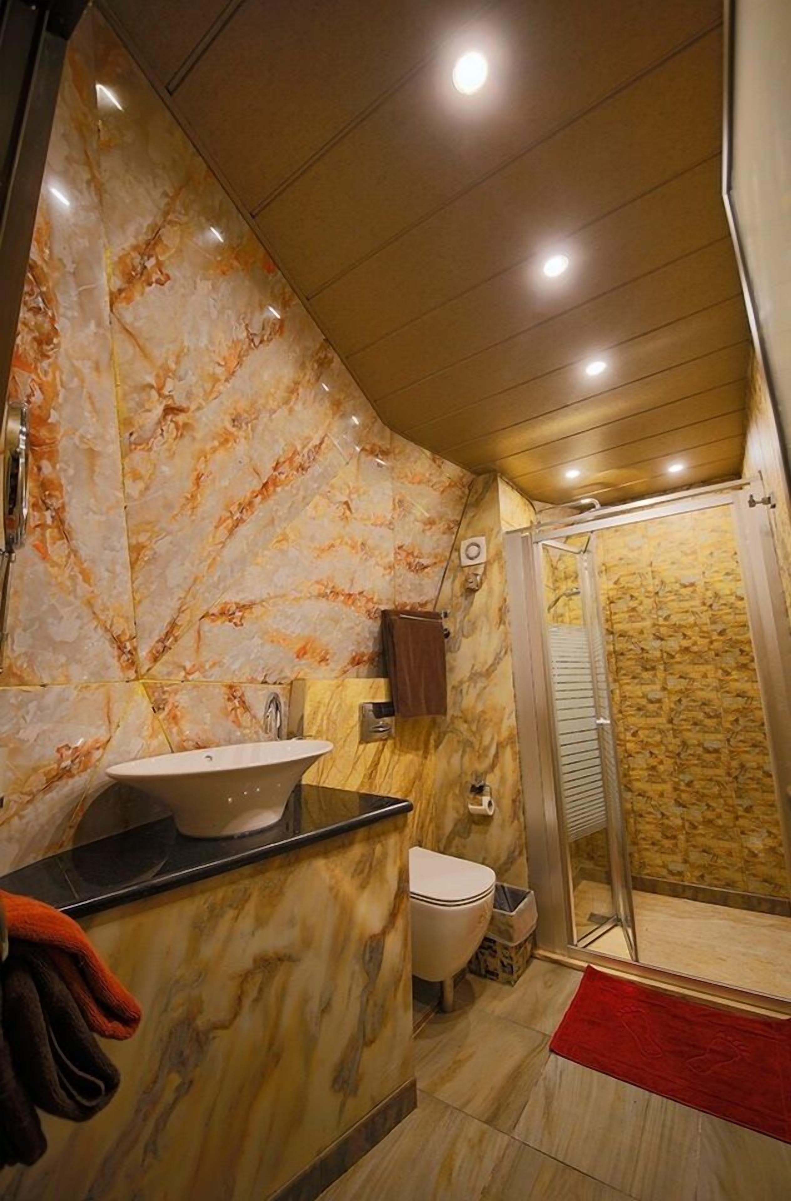 A bathroom with a marble vanity, a toilet, and a shower area.