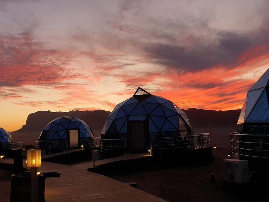 Geodesic dome structures with a walkway leading to them, set against a sunset sky.