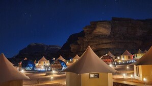 Eine Reihe von kuppelförmigen Zelten mit einem zentralen Gang, vor einer Bergkulisse gelegen.