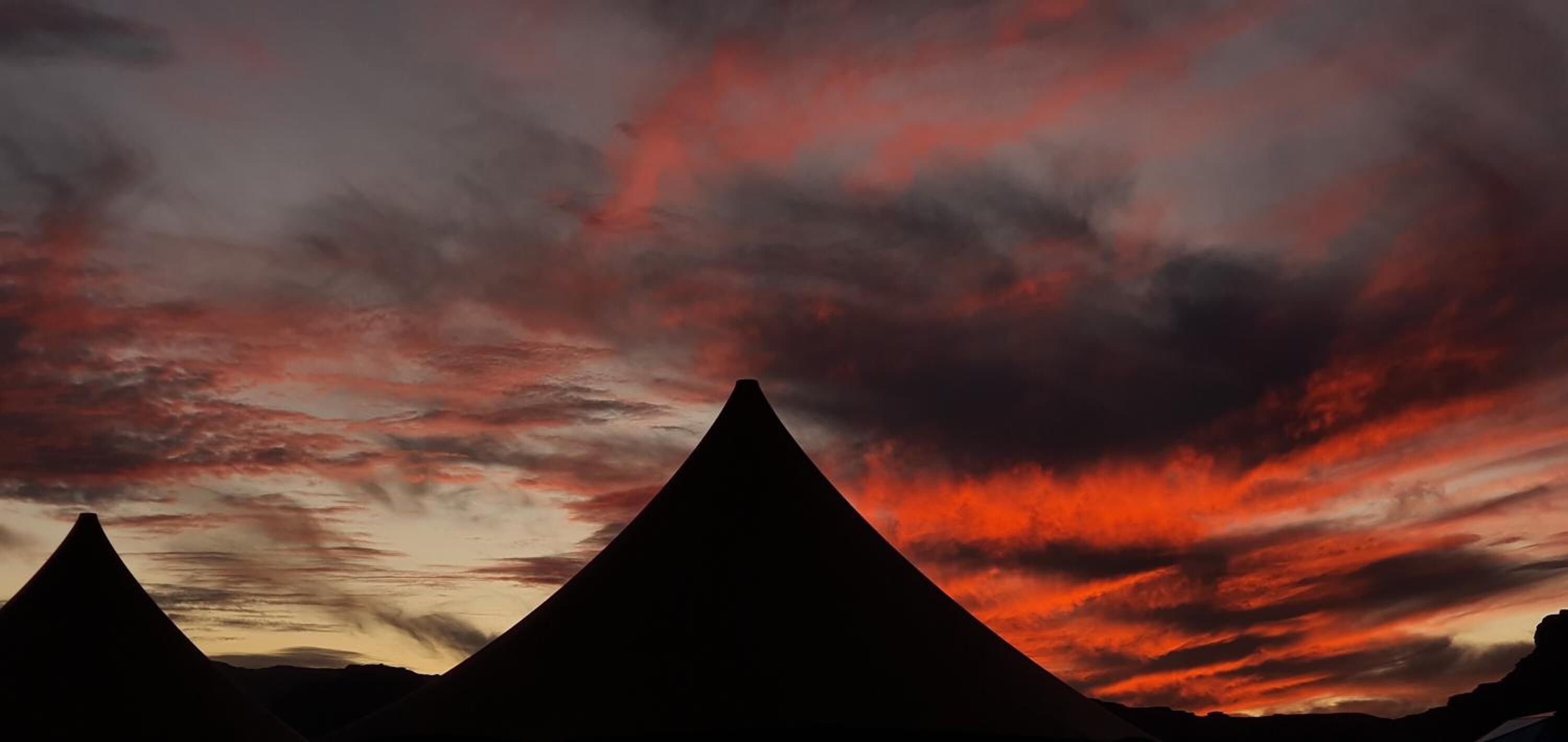 Pyramidimainen rakennelma, jonka siluetti erottuu dramaattisen auringonlaskun taivaalla.