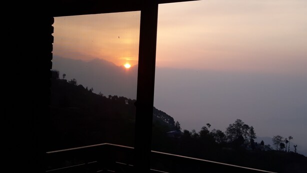 A room with a large window overlooking a sunset.