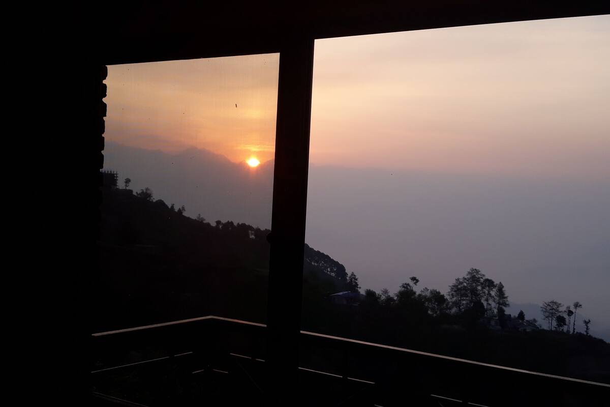Una habitación con un amplio ventanal que da a una puesta de sol.