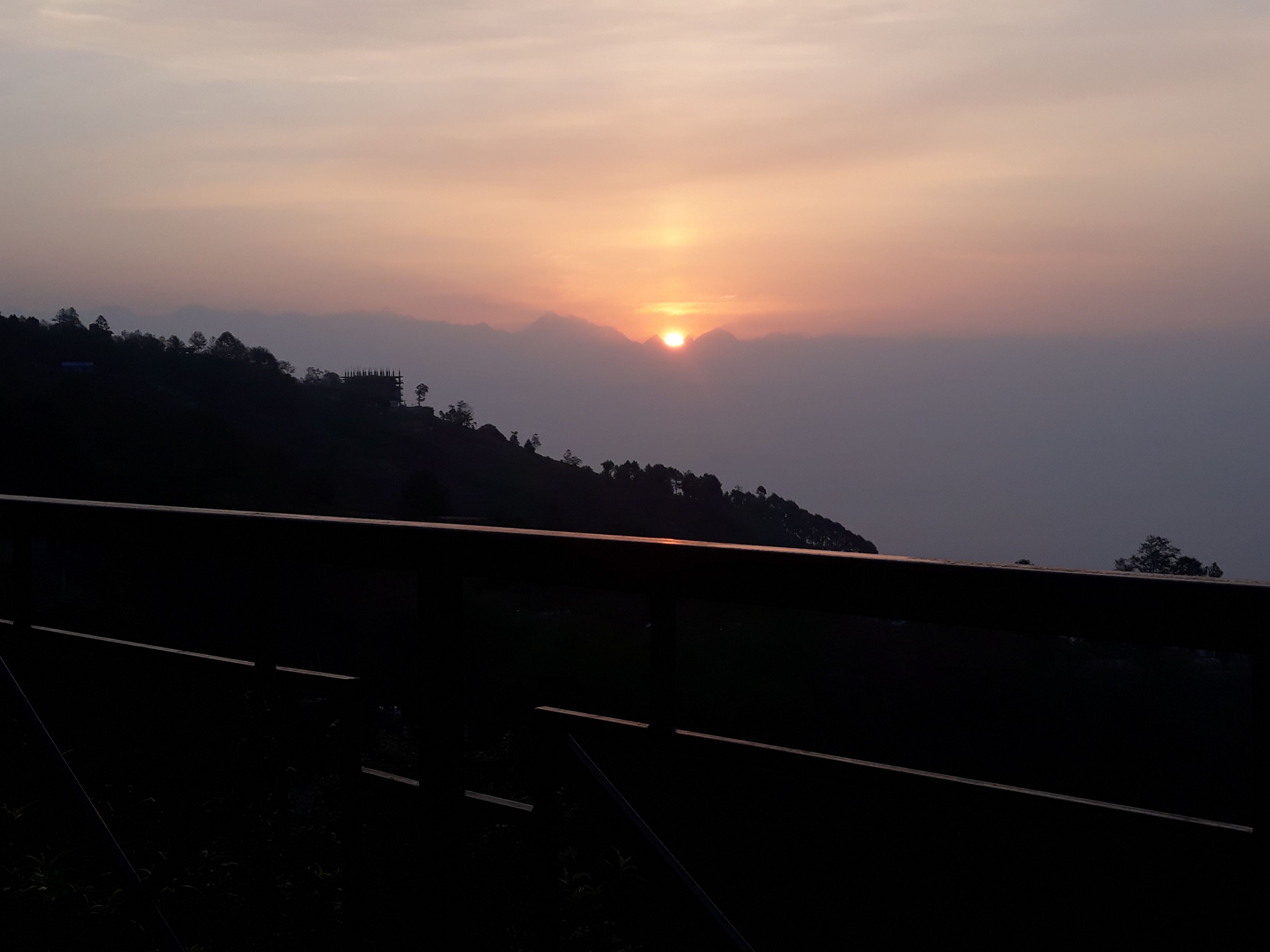 Un atardecer sobre un paisaje montañoso con un puente en primer plano.