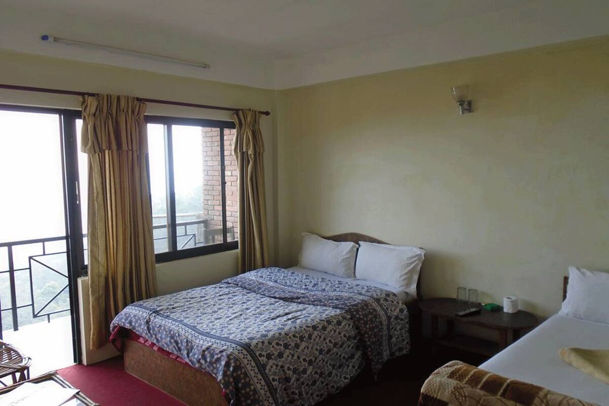 Habitación de hotel estándar con una cama individual, una mesita de noche pequeña, una silla y una ventana con cortinas.
