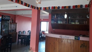A reception area with a wooden counter, a Pepsi refrigerator, and a dining area with chairs and a table.