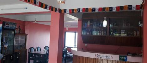Un'area reception con un bancone in legno, un frigorifero per Pepsi e una sala da pranzo con sedie e un tavolo.