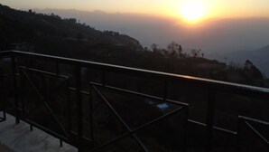 A sunset view from a balcony with a metal railing.