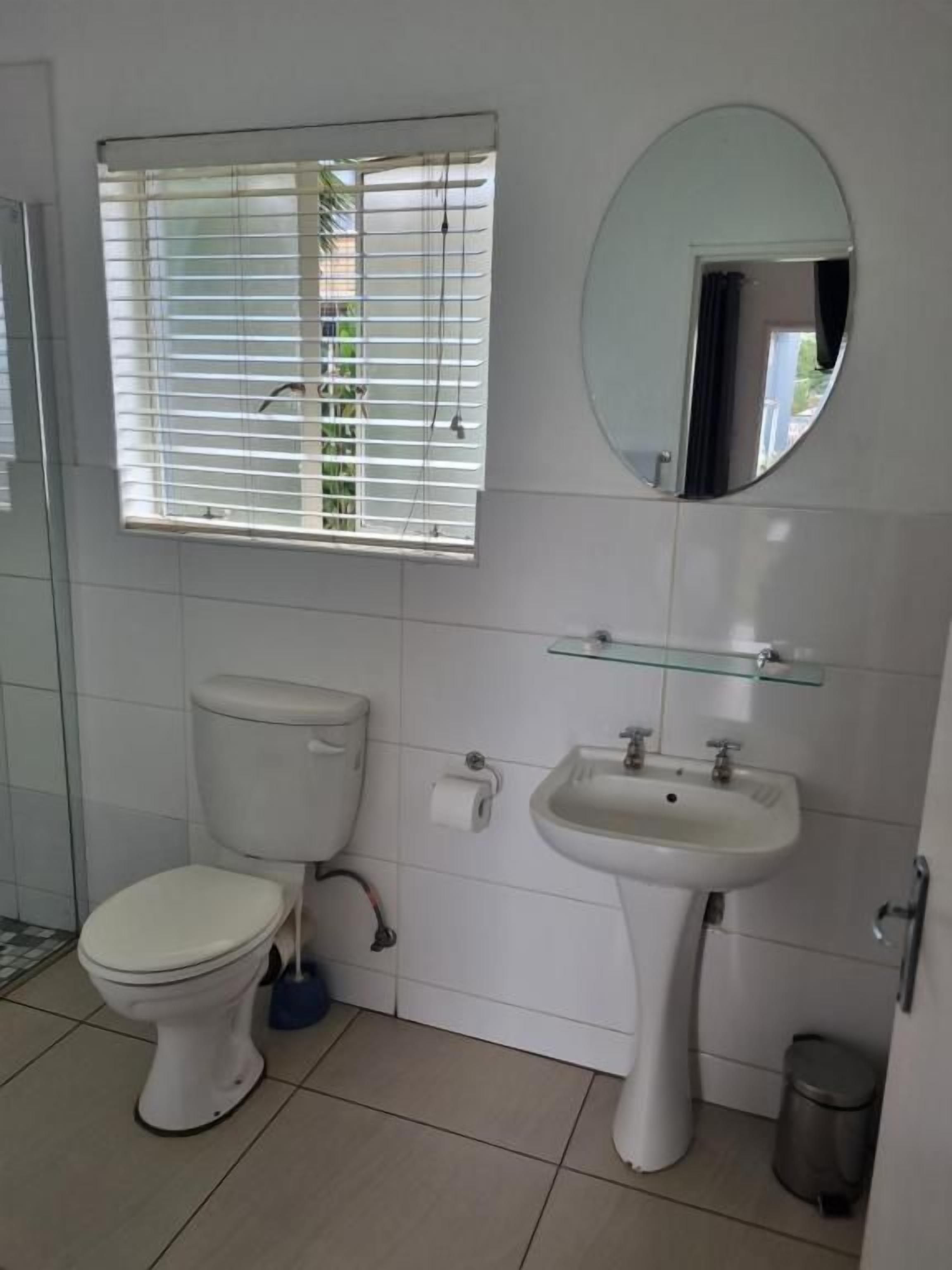 A bathroom with a toilet, sink, and mirror.