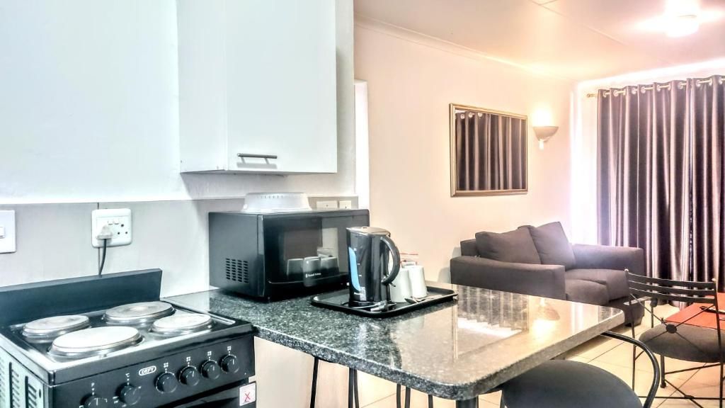 Cocina compacta con estufa, microondas y cafetera. Cuenta con un comedor con mesa y sillas.