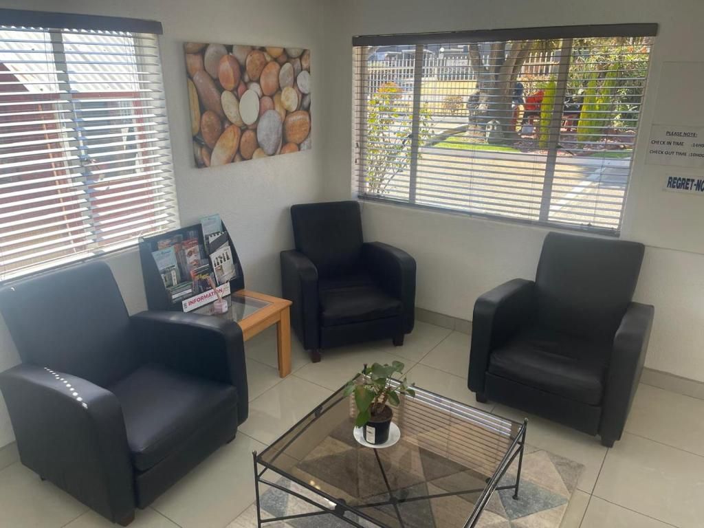 A reception area with three black leather chairs, a glass-top coffee table with a potted plant, and a bulletin board with information pamphlets.