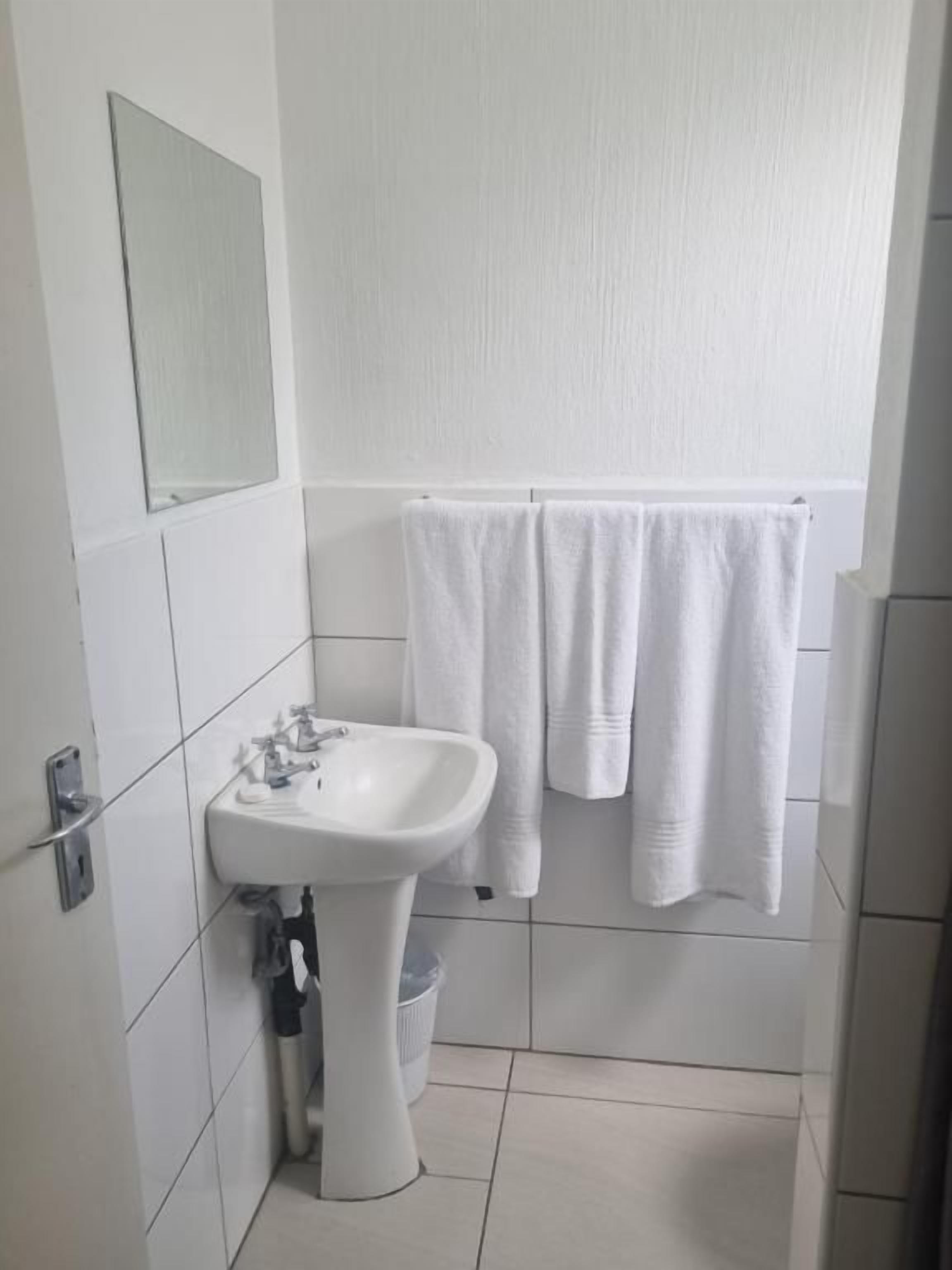 A bathroom with a white sink, a mirror, and a towel rack with two towels.
