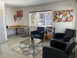 A waiting area with a reception desk, a coffee table, and seating. - Palmar Hotel (Kempton Park)