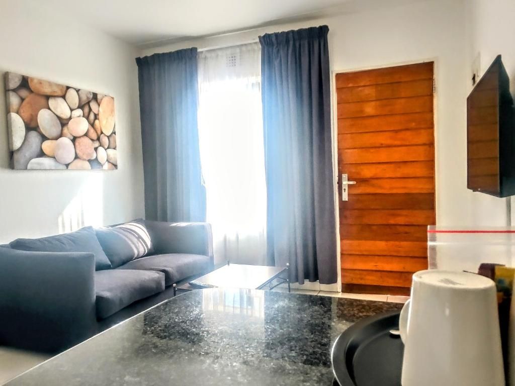 Una sala moderna con un sofá oscuro, una mesita de centro y una puerta de madera.