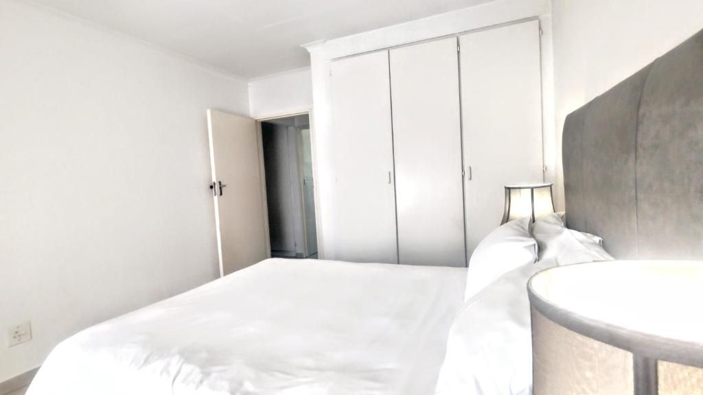 Habitación de hotel con una cama, una mesita de noche, una lámpara y un armario.