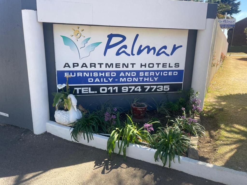 A sign for 'Palmar Apartment Hotels' with contact information and a list of services.