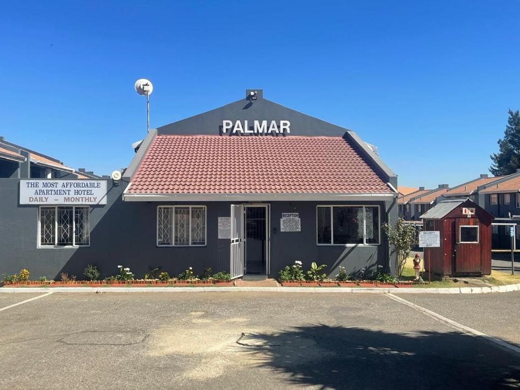 A small building with a sign that reads 'PALMAR' and another sign stating 'THE MOST AFFORDABLE APARTMENT HOTEL DAILY - MONTHLY'.