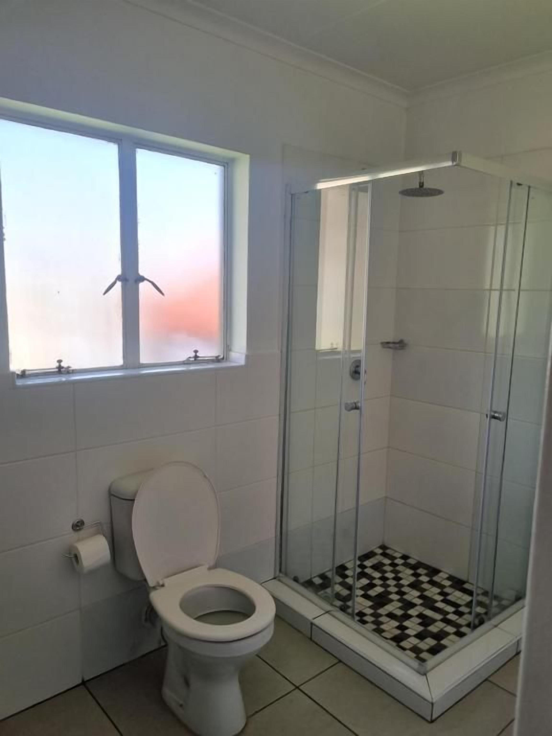 Un bagno con il water, una doccia con porta in vetro e una finestra vista panoramica.