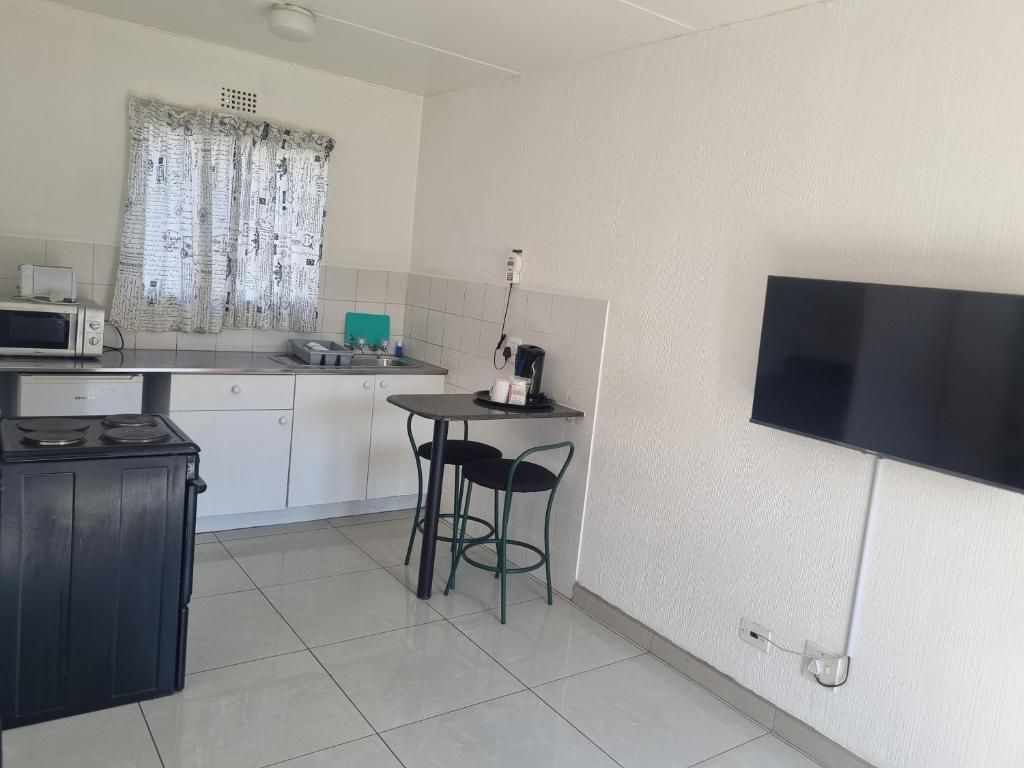 A compact kitchen with a microwave, stove, and a small dining area with two chairs.