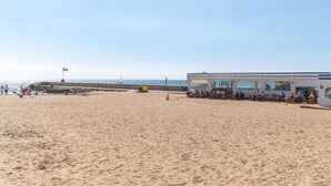 A beach with a building that has multiple rooms and a dining area.