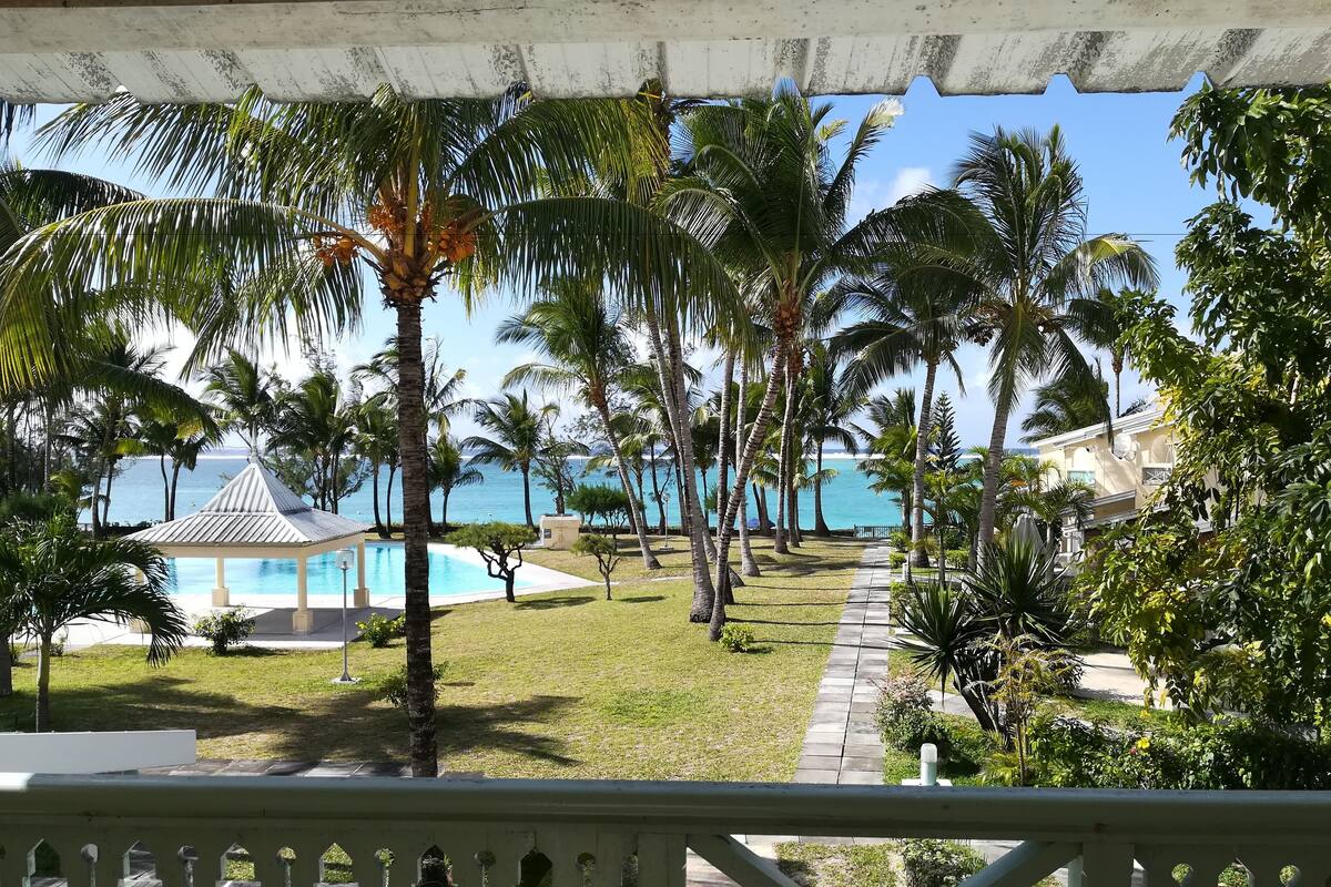 A resort with a pool, palm trees, and a view of the ocean.