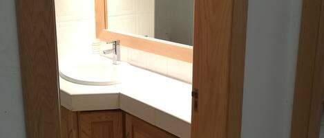 Un baño con un mueble de madera, un lavabo blanco y un espejo encima.