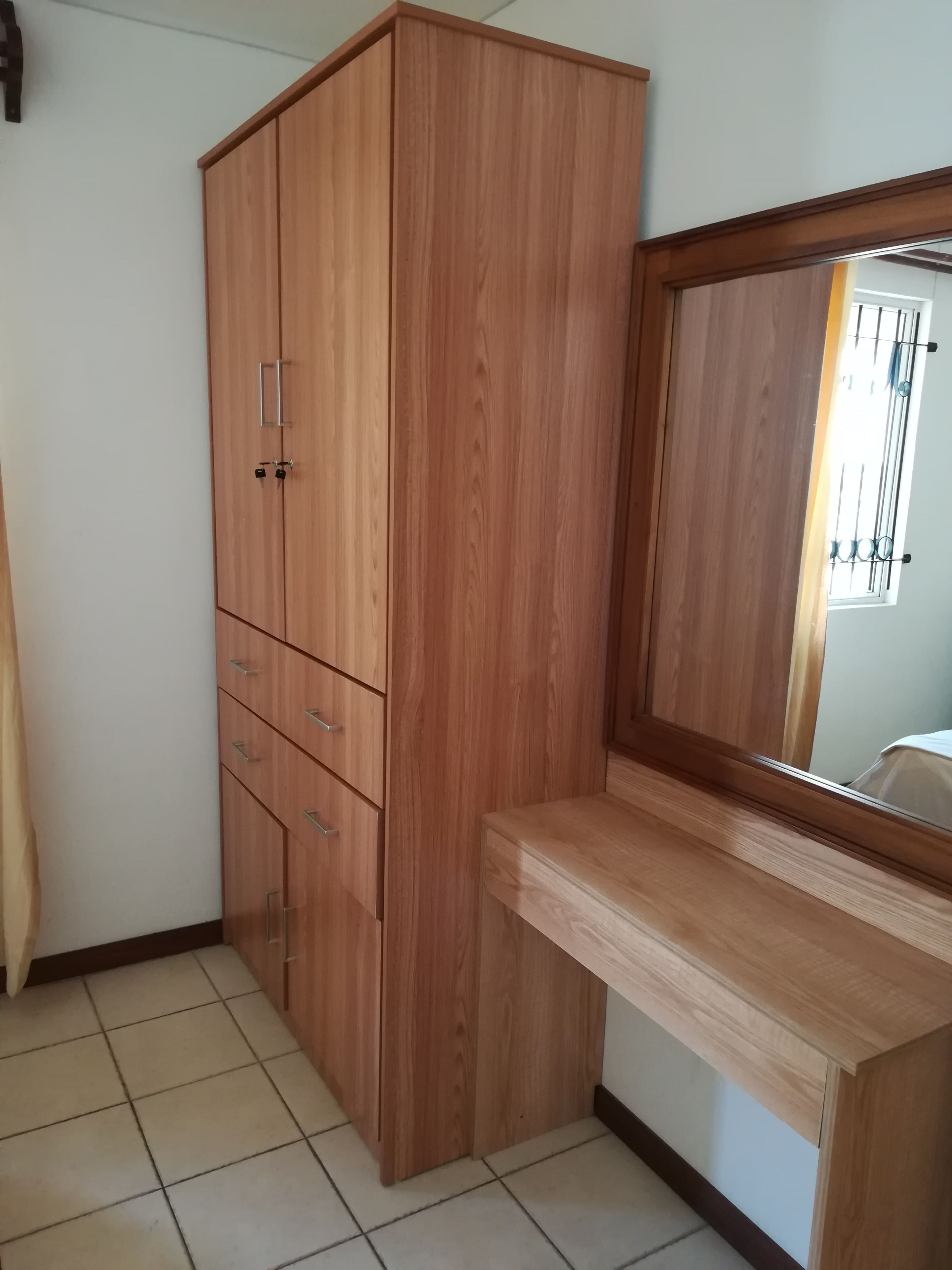 Ein Zimmer mit einem Holzschrank, einem Spiegel und einem Fliesenboden.
