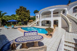 A pool area with a tiled deck, a lounge chair, and a decorative table. - La Perla - sea view villa with private pool in Moraira (Moraira)