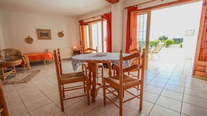 A dining area with a table and chairs, a view to the outside, and a window with curtains.