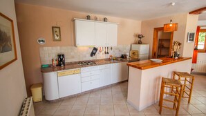A kitchen with white cabinets, a stove, a sink, and a small island with stools.