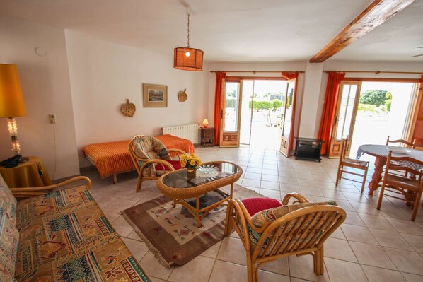 A cozy living room with a sofa, a round table, and wicker chairs. There is a lamp, a framed picture, and a window with curtains. - La Perla - sea view villa with private pool in Moraira (Moraira)