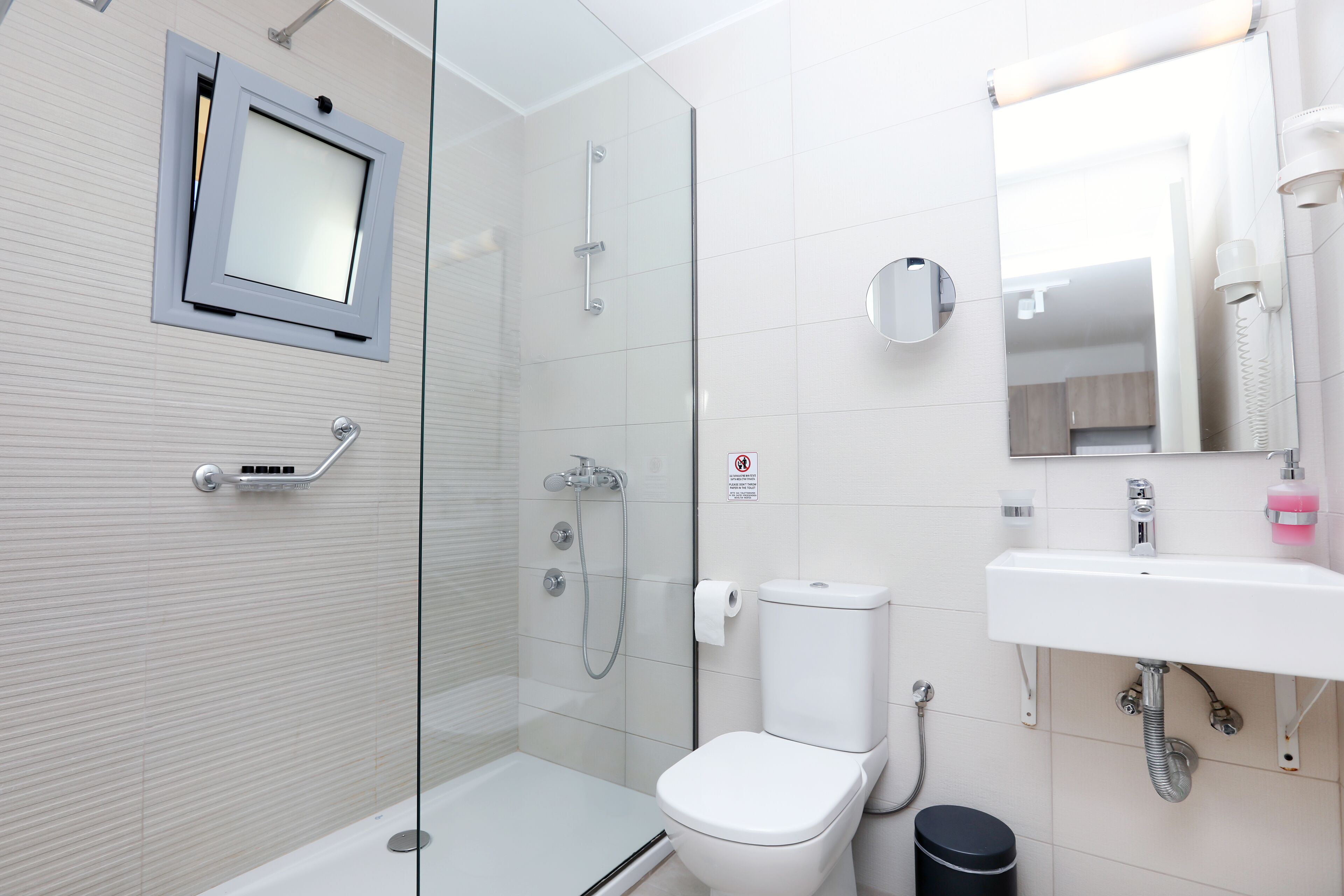 Une salle de bain moderne avec une douche à parois de verre, des toilettes, un lavabo et un miroir.