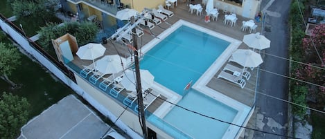 Vista aérea de um hotel com piscina, área de estar externa e um terraço coberto.