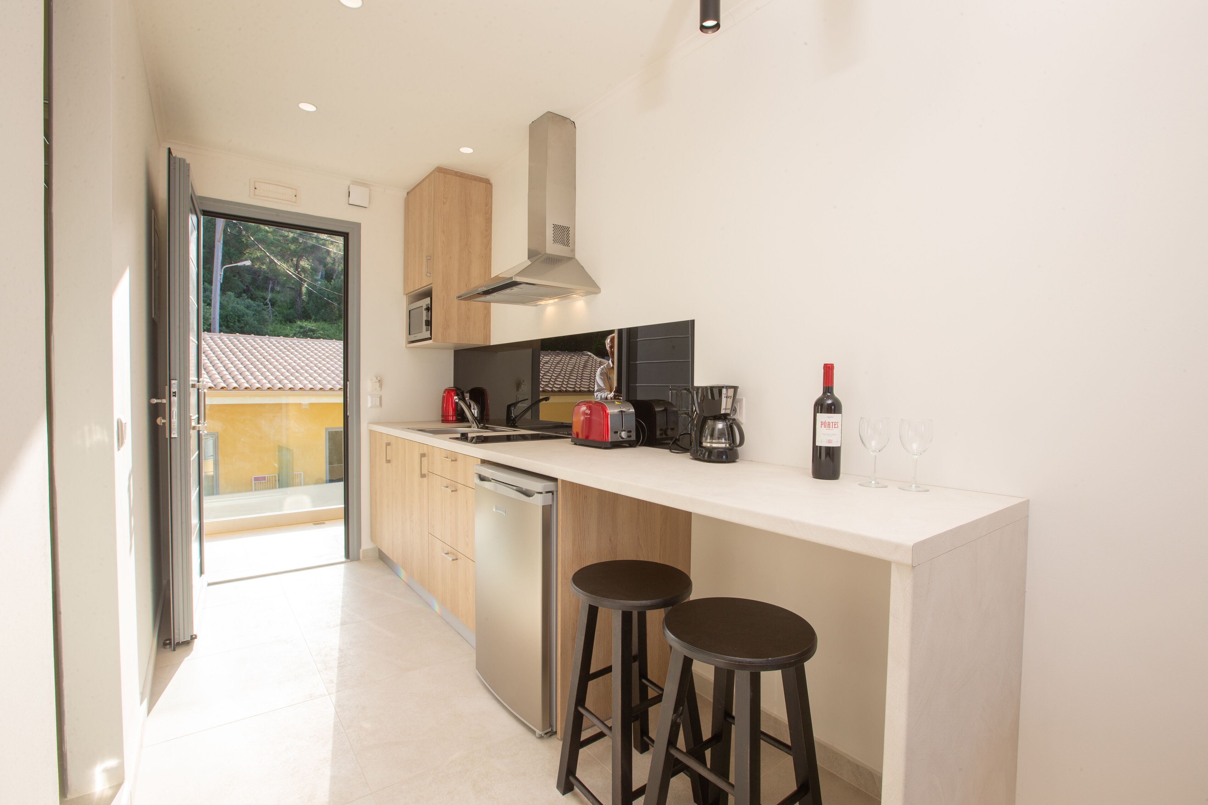 A modern kitchen with a large island, bar stools, a coffee maker, and a wine bottle.