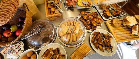 A buffet with various food items including fruits, pastries, and sandwiches.