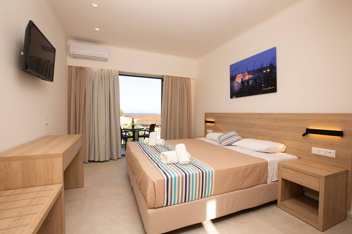 A hotel room with a bed, bedside table, and a TV mounted on the wall.