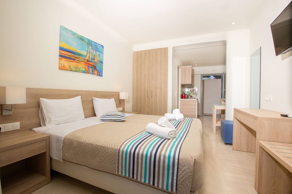 A modern hotel room with a large bed, a desk, and a television.