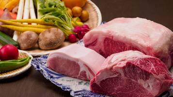Une variété de légumes frais et deux morceaux de viande sont disposés sur une table en bois.