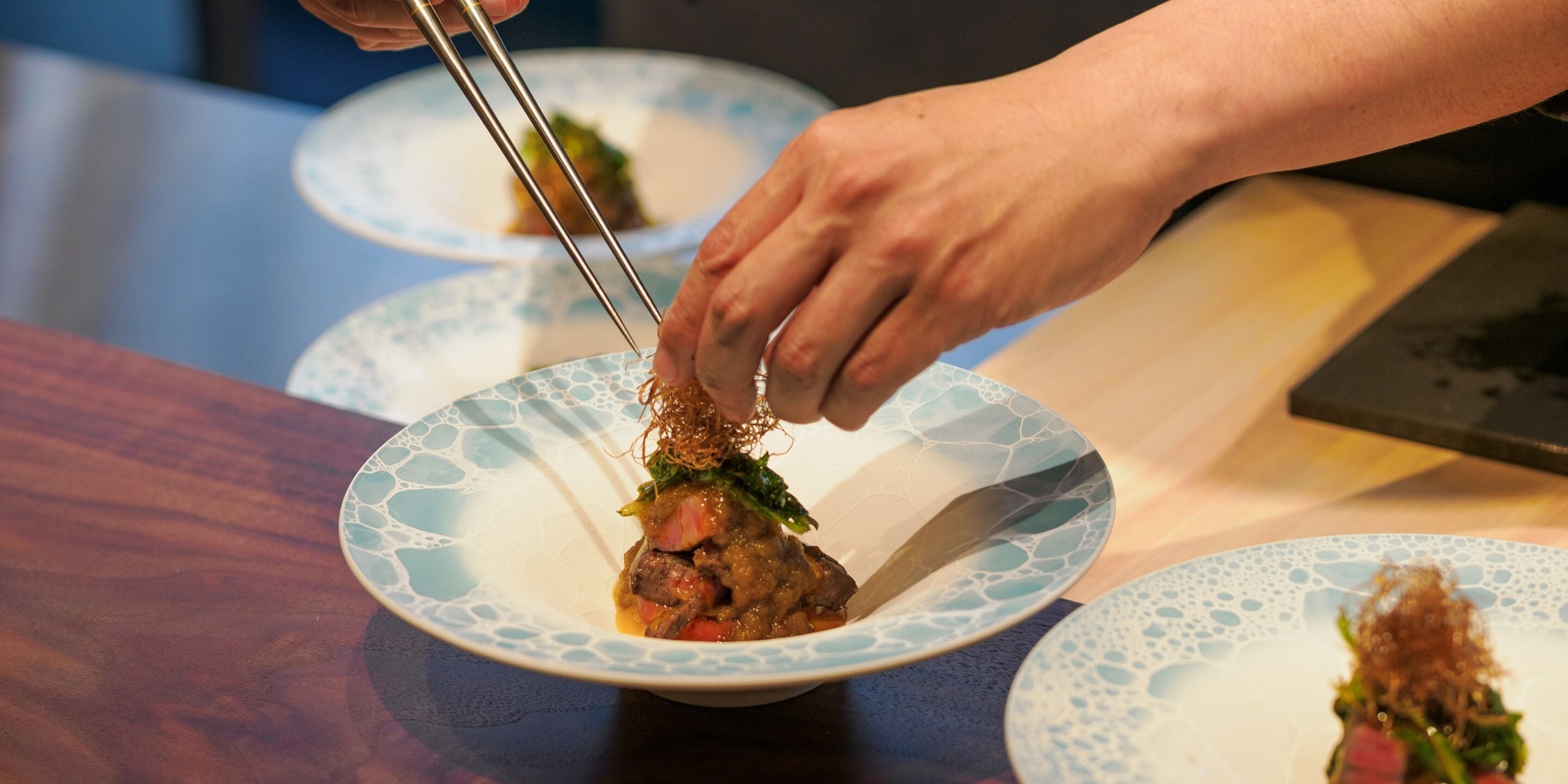 A person using chopsticks to pick up food from a plate.