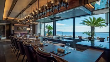 Un restaurante con una larga mesa de comedor, sillas y vista al mar.
