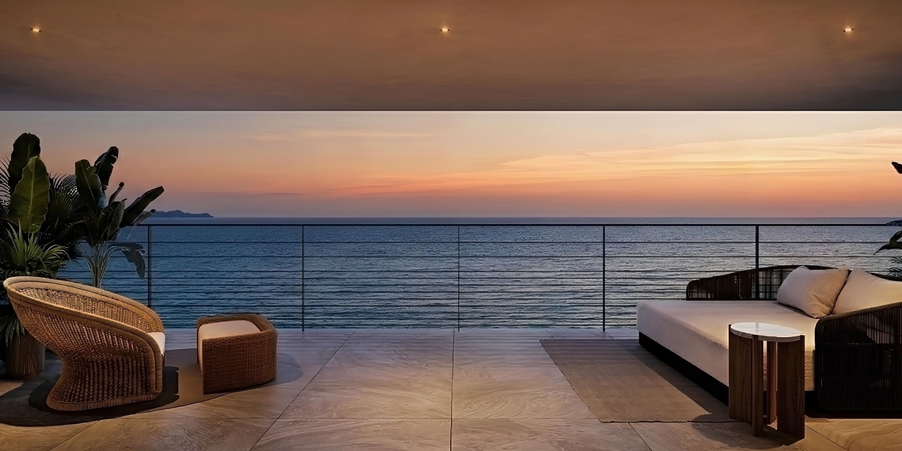 Un balcón con vista al mar al atardecer, con muebles de mimbre y un sofá.