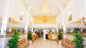 A hotel lobby with a chandelier, seating area, reception desk, and a large mirror wall. - Nu Hoang Hotel (Phan Rang)