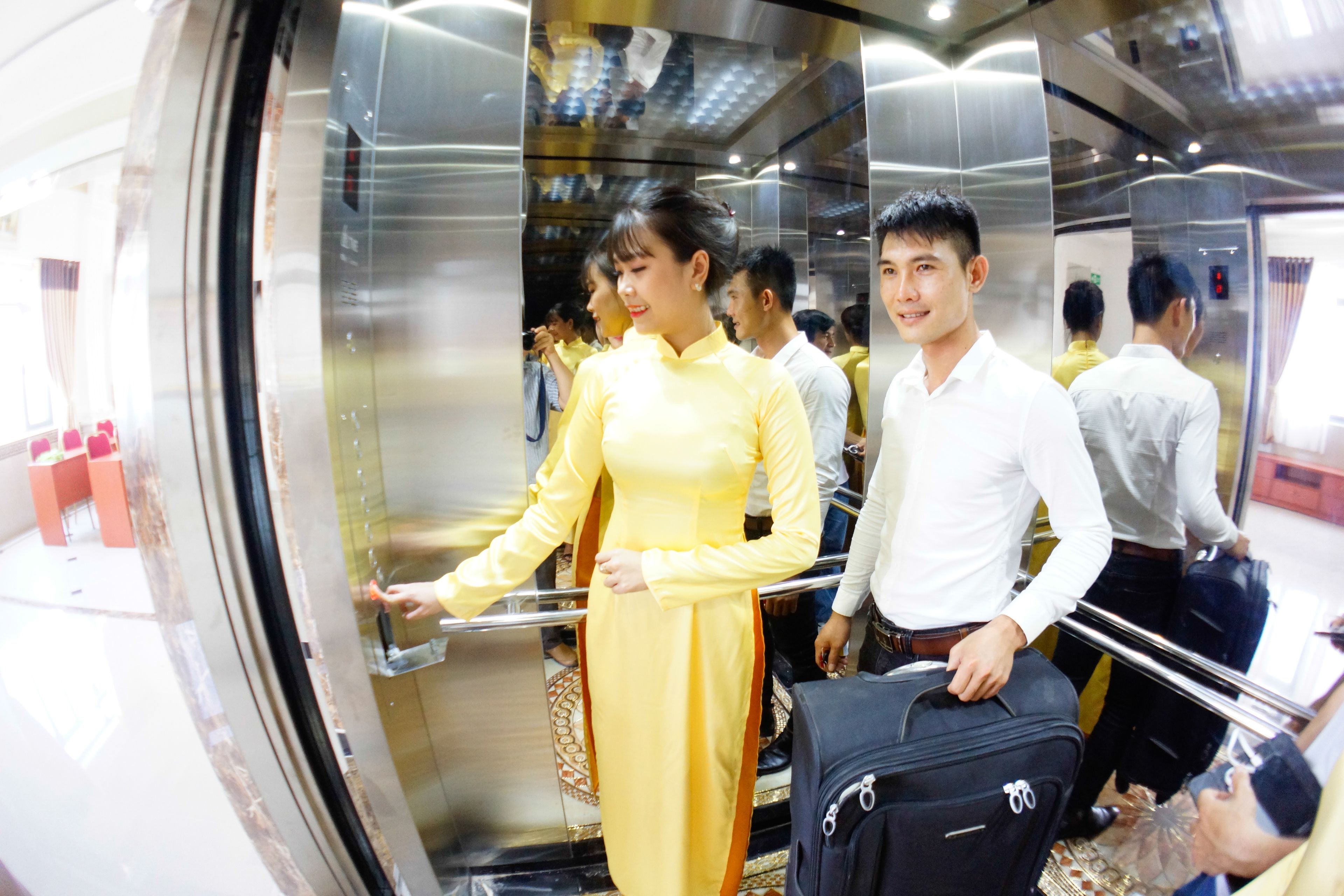 Un grupo de personas en un ascensor con paredes metálicas y superficie reflectante.